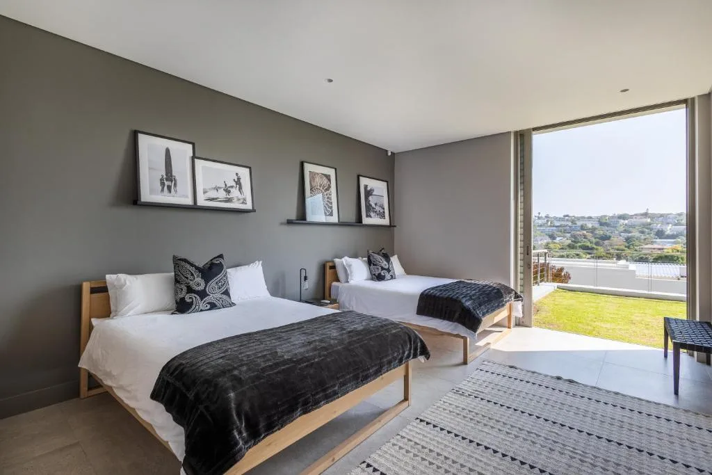 Spacious bedroom with two beds, framed wall art, and scenic lagoon view