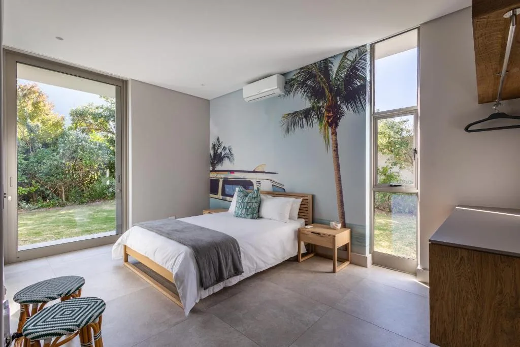 Modern bedroom with queen bed, palm plant, garden views through sliding doors