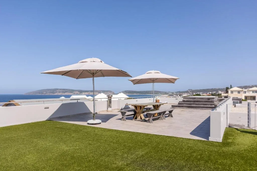 Expansive patio with umbrellas and seating overlooking coastal views