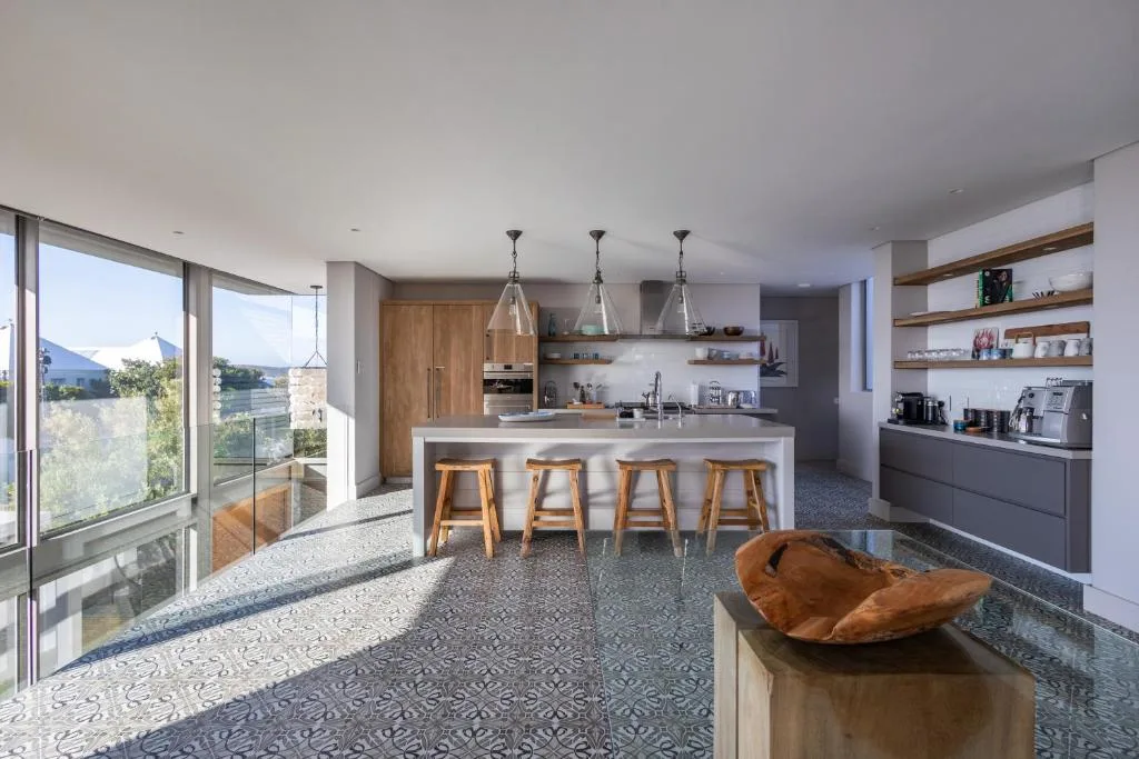 Modern kitchen with island seating, wooden cabinetry, and mountain views through large windows