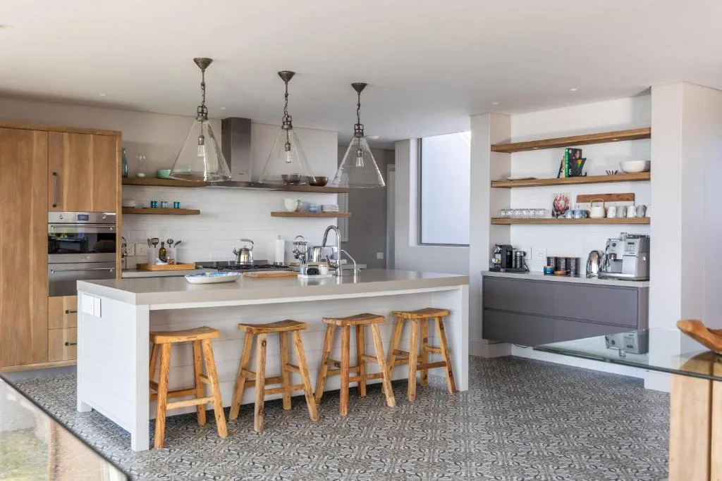 Modern kitchen with white island, wooden stools, and pendant lighting