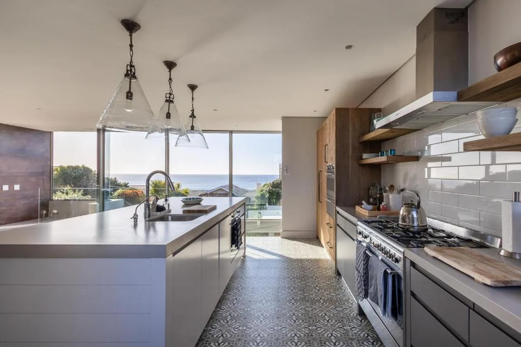Modern kitchen with island, gas stove, and ocean views through large windows
