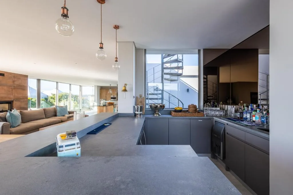 Modern open-plan kitchen with dark cabinetry and pendant lighting overlooking lounge