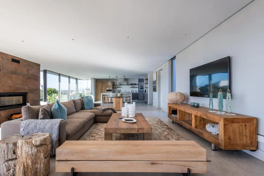 Modern living room with brown sofa, wooden furniture, and mountain views