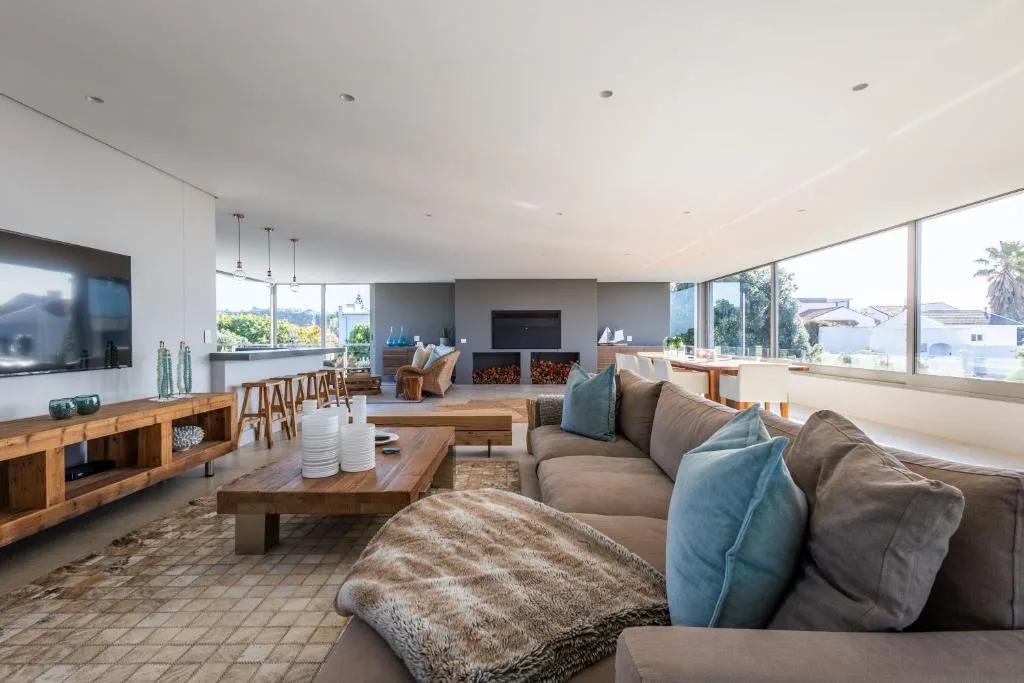 Spacious modern lounge with large sectional sofa, fireplace, and panoramic windows