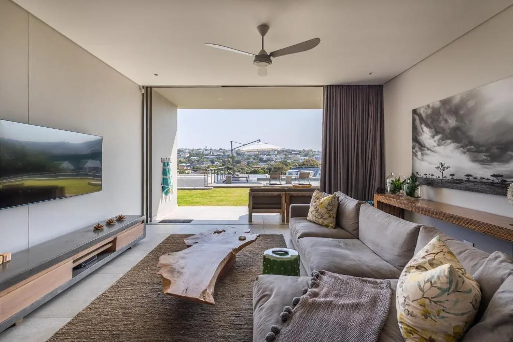 Modern lounge with gray sofa, TV, and expansive deck views overlooking town