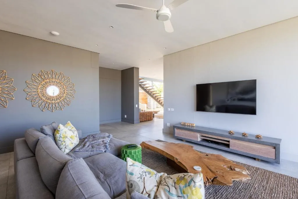 Modern living room with grey sofa, wall-mounted TV, and decorative gold wall art