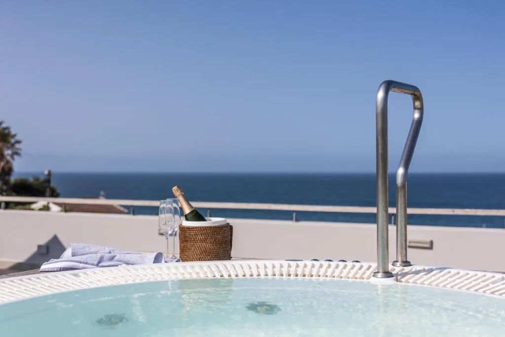 Hot tub with ocean view, champagne bucket, and coastal deck beyond