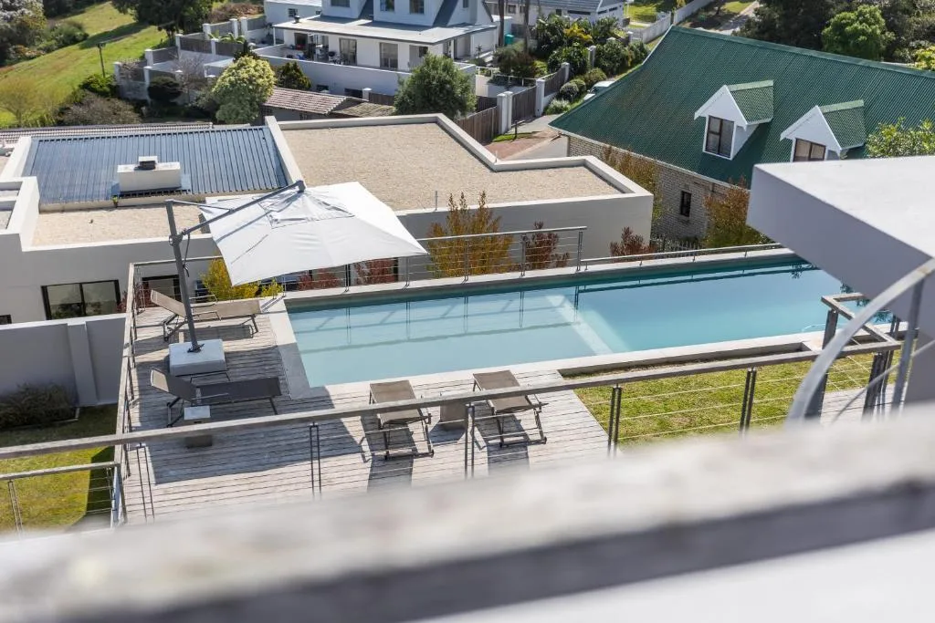 Sparkling turquoise swimming pool with loungers and umbrella shade.