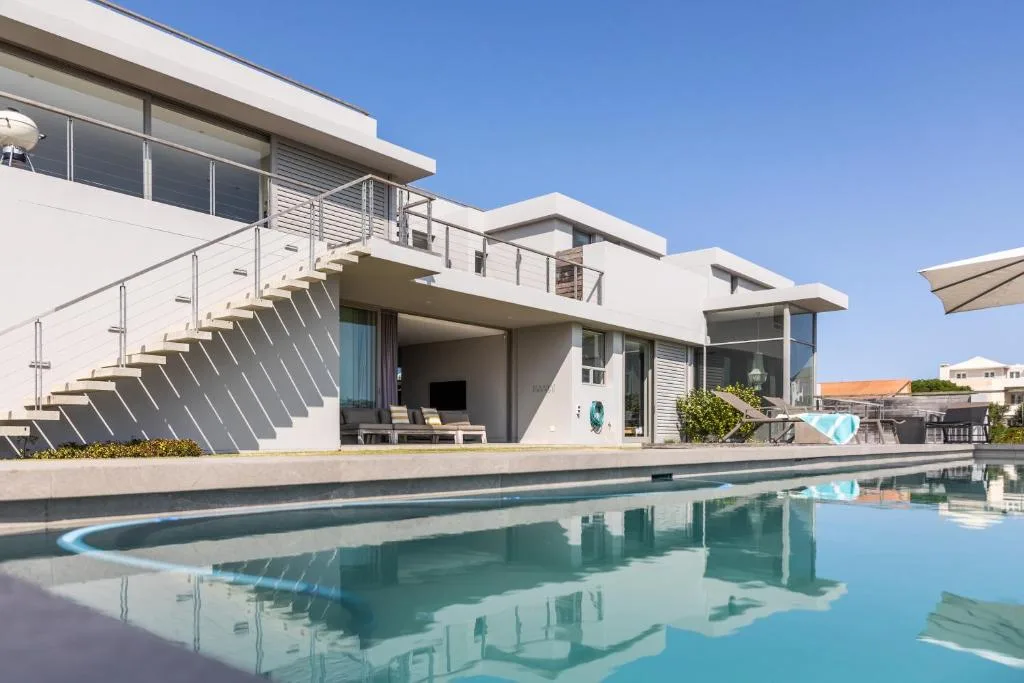 Modern villa with swimming pool reflecting the contemporary architecture and clear blue sky