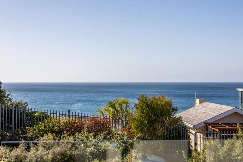 Expansive ocean view with coastal vegetation and property structure visible