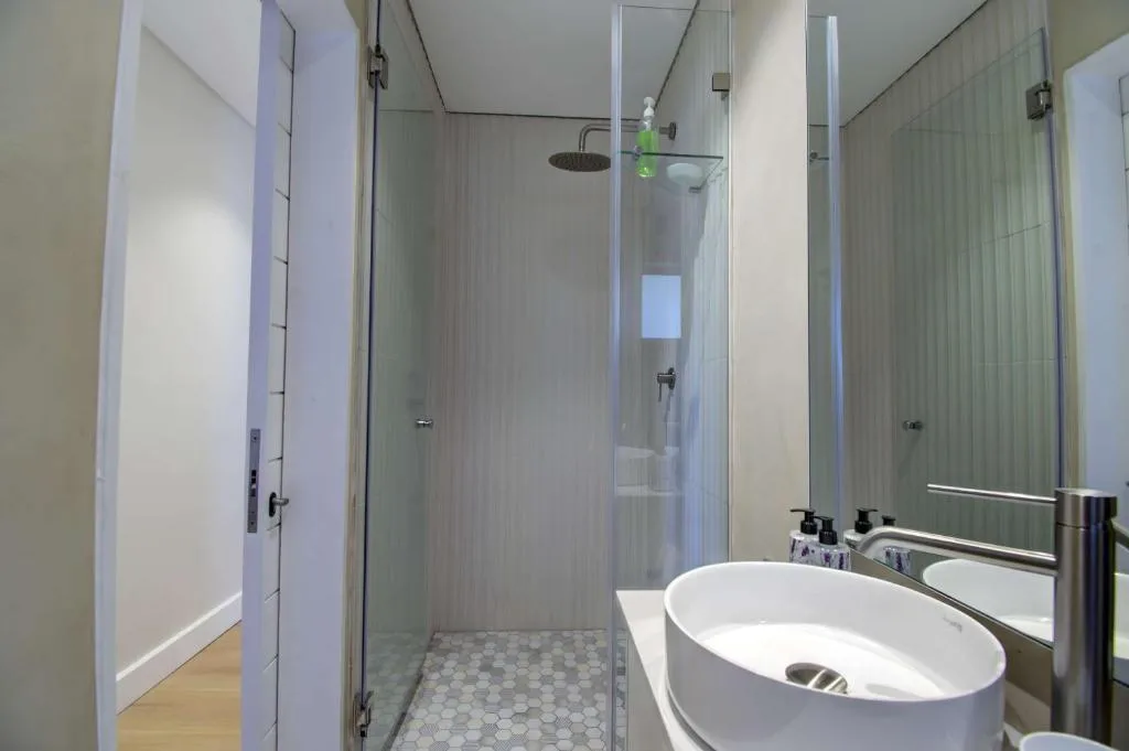 Modern bathroom with rainfall showerhead, oval basin sink, and glass enclosure