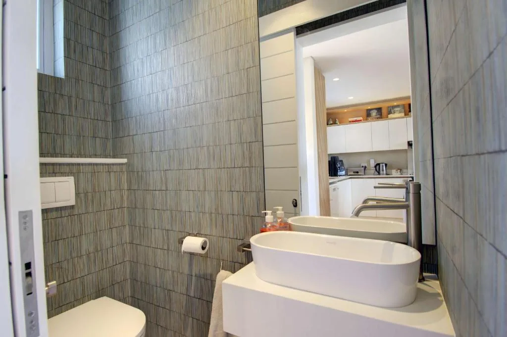 Modern bathroom with dual white vessel sinks and gray tile walls