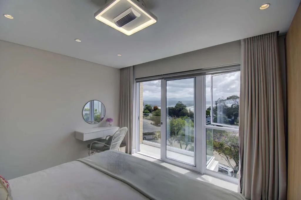 Modern bedroom with panoramic sea views through large sliding glass doors