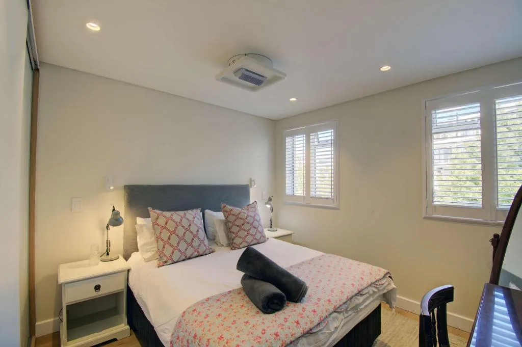 Modern bedroom with queen bed, patterned pillows, and shuttered windows
