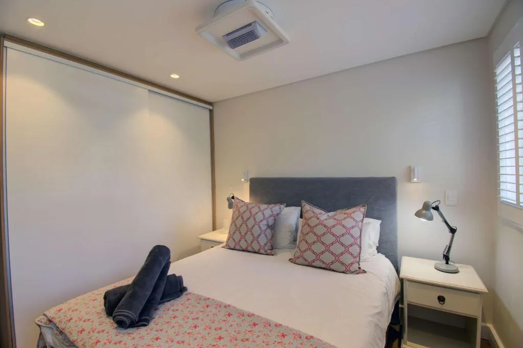 Bedroom with queen bed, patterned pillows, bedside lamp, and mirrored wardrobe