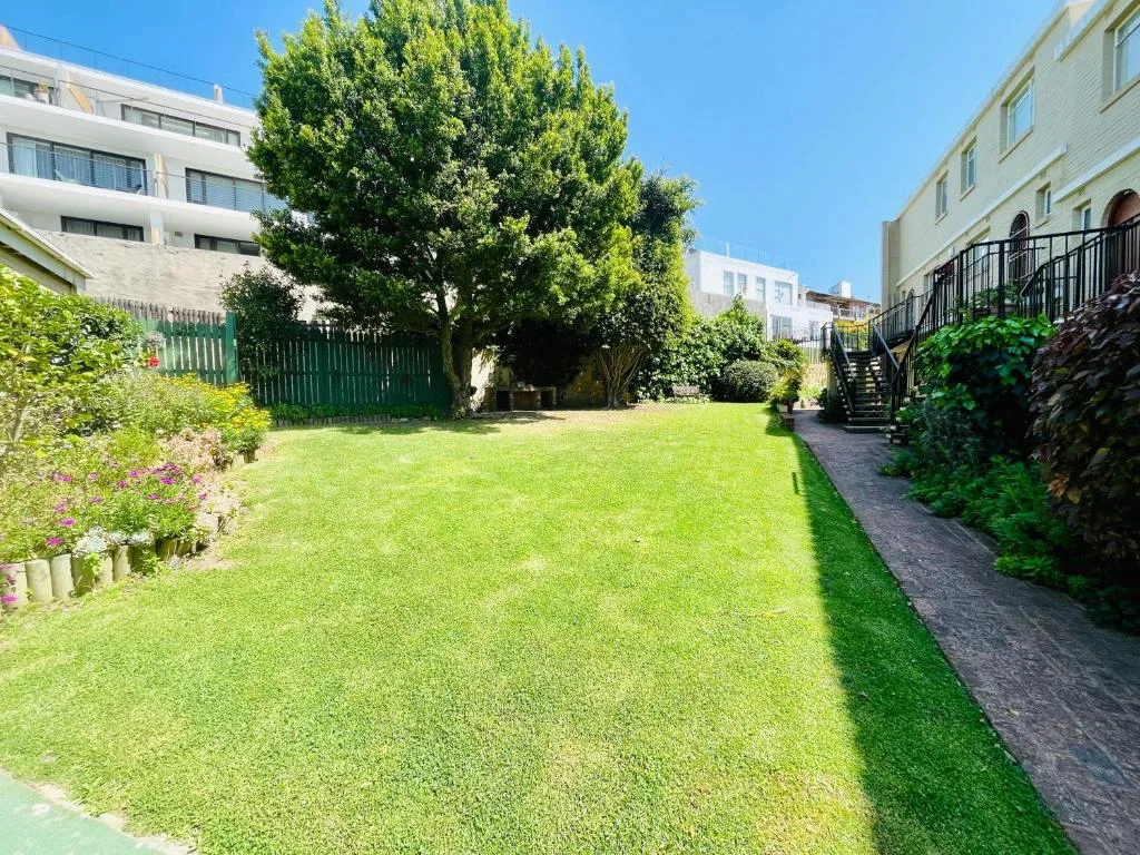 Lush garden lawn with flowering borders and mature trees surrounding property
