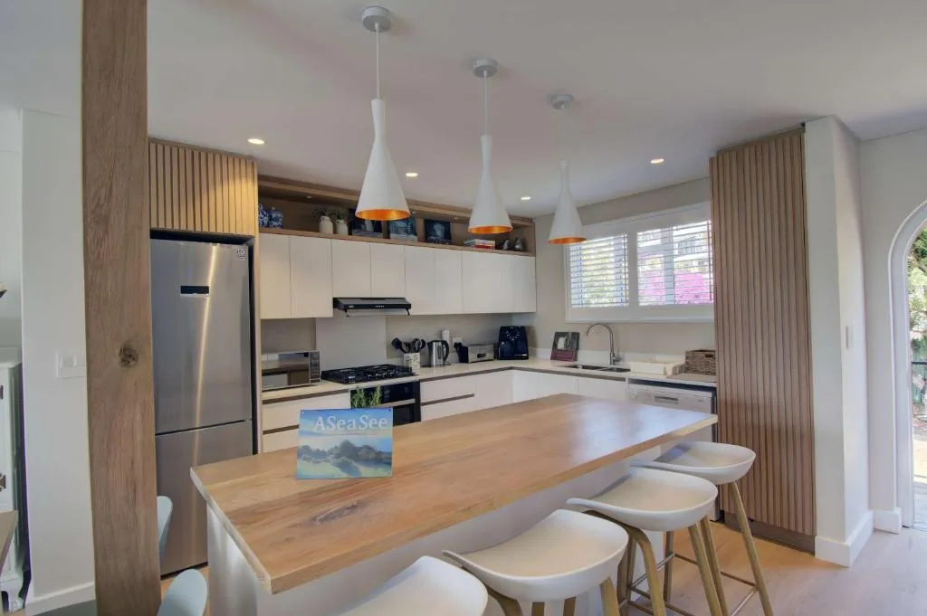 Modern kitchen with white cabinetry, wooden island counter, stainless steel appliances