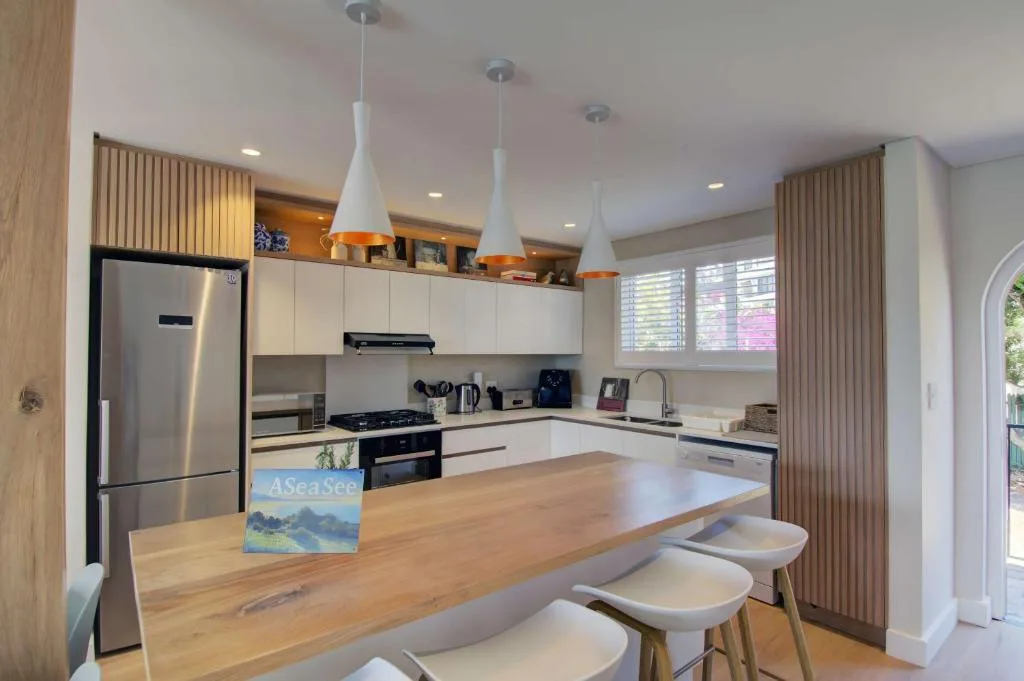 Modern kitchen with white cabinetry, stainless steel appliances, and wooden island counter