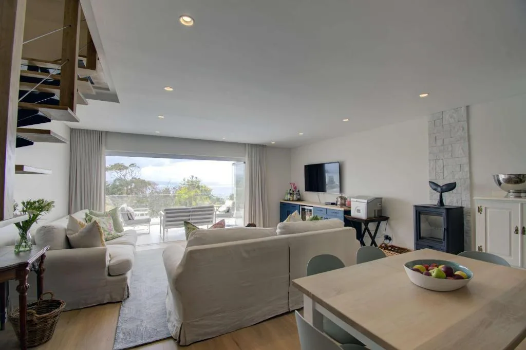 Bright open-plan lounge with cream sofas, fireplace, and mountain views through glass doors