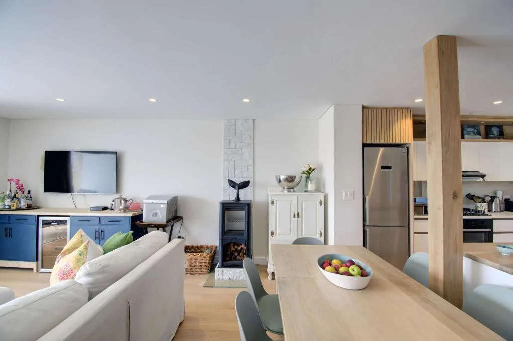 Open-plan lounge and kitchen with cream sofa, stainless steel appliances, and modern decor