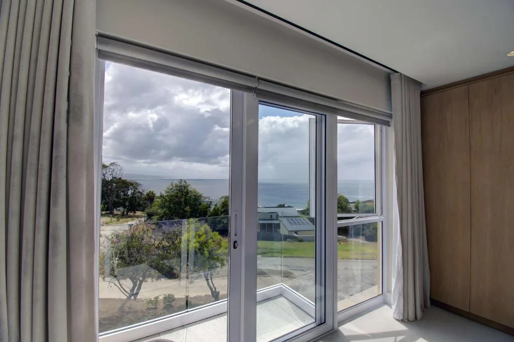 Ocean and coastline view through large glass doors with curtains