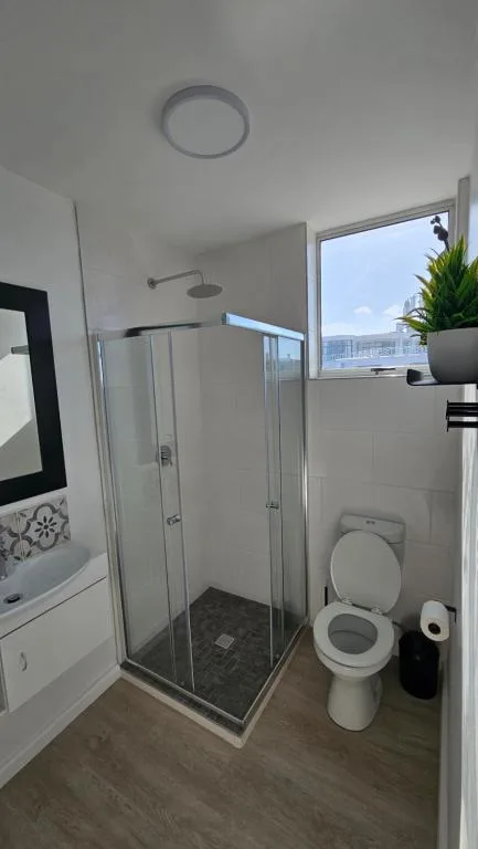 Modern bathroom with glass shower enclosure, toilet, and ocean view window