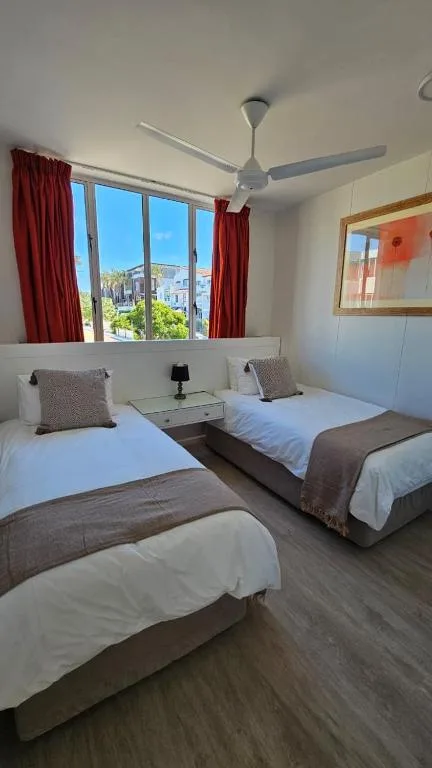 Bright bedroom with three single beds and garden route town views through large windows
