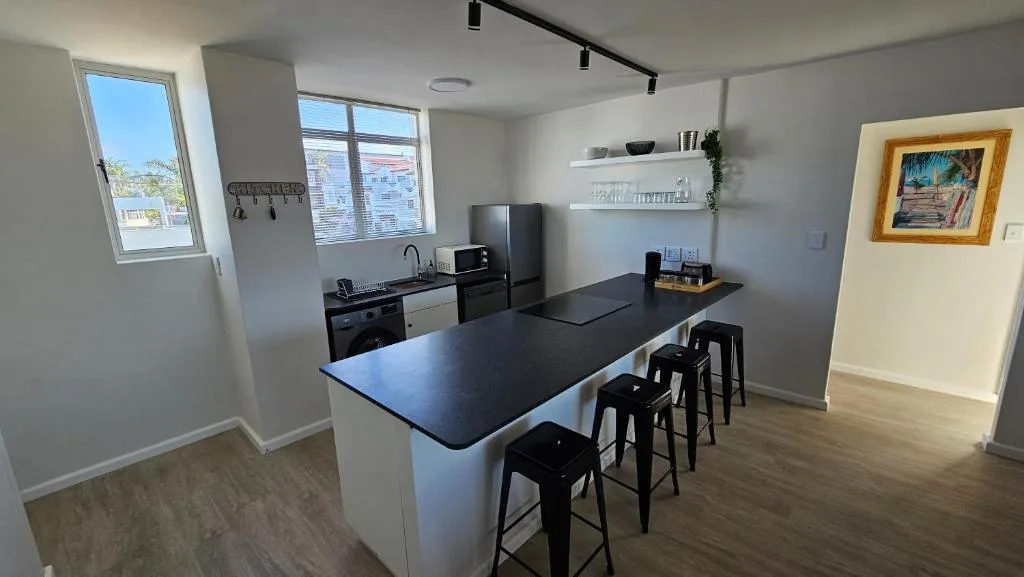 Modern kitchen with black countertop island, bar seating, and stainless steel appliances