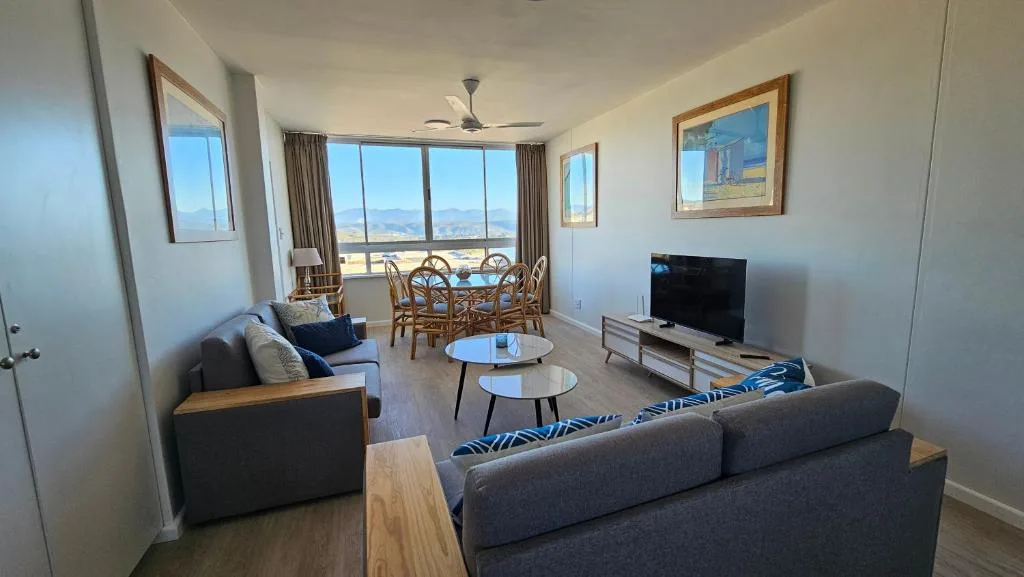 Spacious open-plan lounge with sofas, TV, and panoramic window views