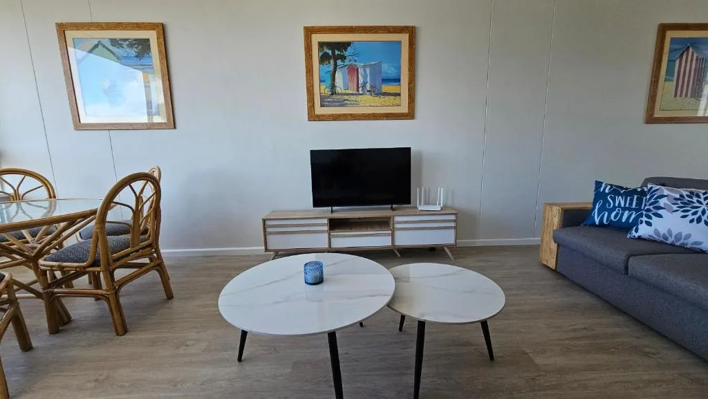 Modern lounge with blue sofa, round white tables, and flat-screen TV