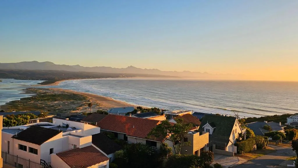 Sunset coastal view over Plettenberg Bay beach with mountains and residential area