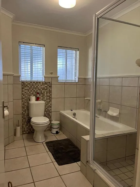 Bright bathroom with toilet, bathtub, shower cubicle, and windows
