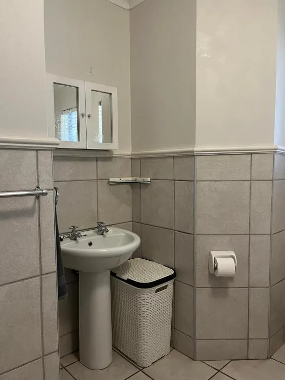 Bathroom with pedestal sink, mirror cabinet, and tiled walls