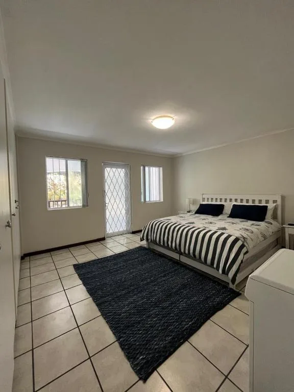Spacious bedroom with queen bed, striped duvet, and patio doors