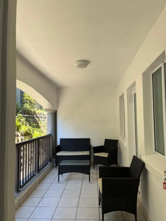Covered patio with black wicker furniture and garden view