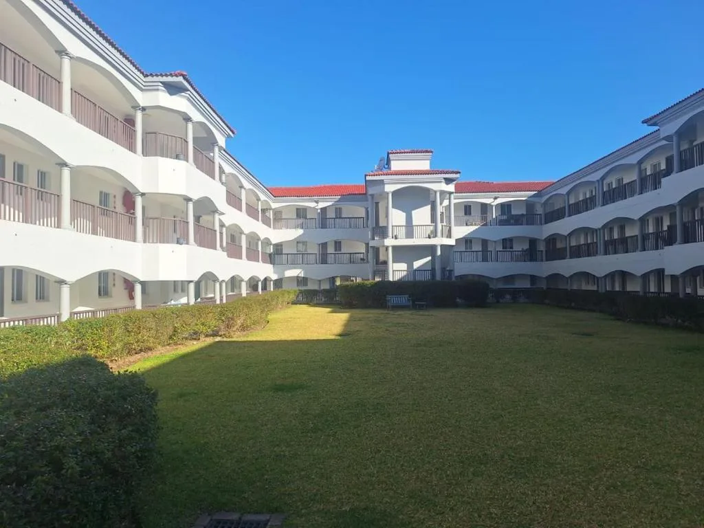 White multi-story apartment complex with red roofs and manicured gardens