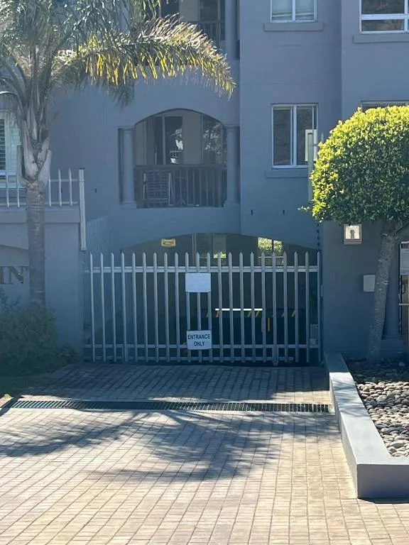 Modern blue apartment building with gated driveway entrance and landscaping