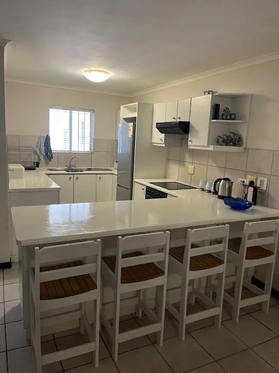 Open-plan kitchen with white cabinetry, island bench, and dining seating