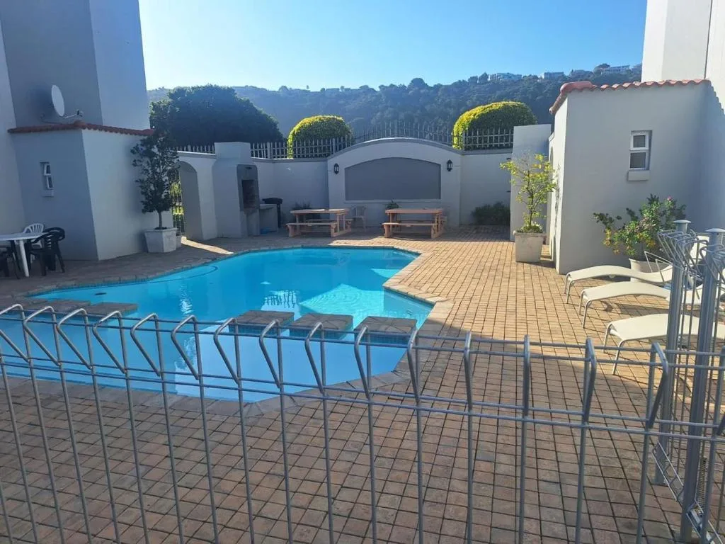 Bright blue swimming pool with surrounding brick patio and lounge chairs