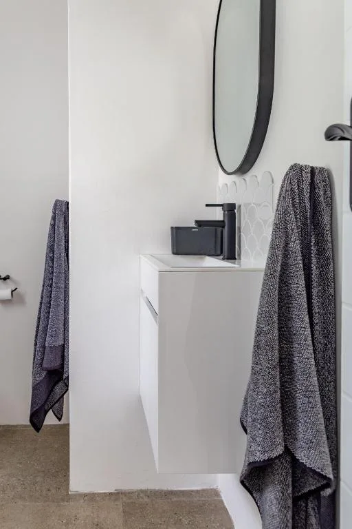 Modern bathroom vanity with round mirror and dark fixtures