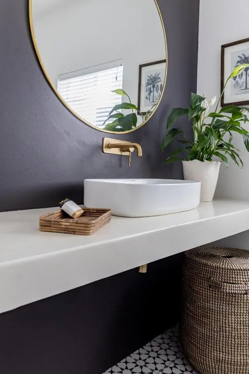 Modern bathroom vanity with round white sink and brass mirror