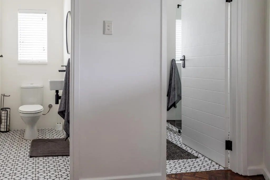 Modern bathroom with walk-in shower, toilet, and patterned tile flooring