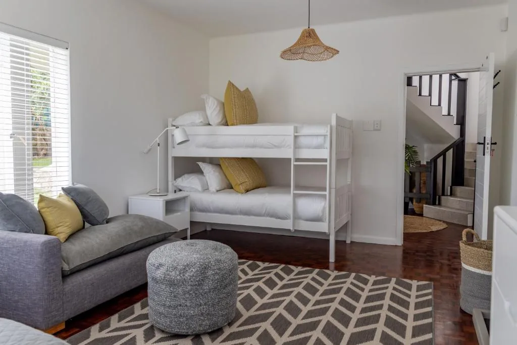 Bright bedroom with white bunk beds, sofa, and modern decor accents