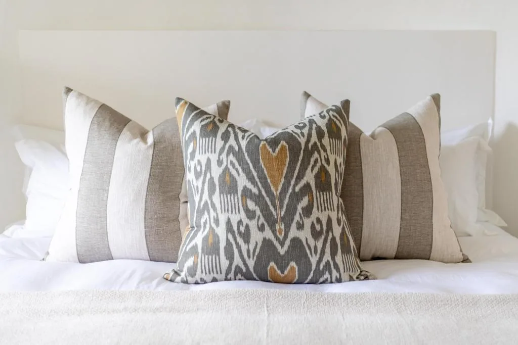 Bed with decorative striped and patterned throw pillows in neutral tones