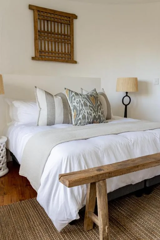 Bright bedroom with white bedding, patterned pillows, wooden bed frame