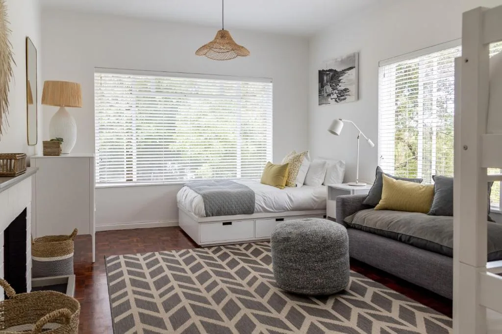 Modern bedroom with bed, seating area, and large windows with shutters