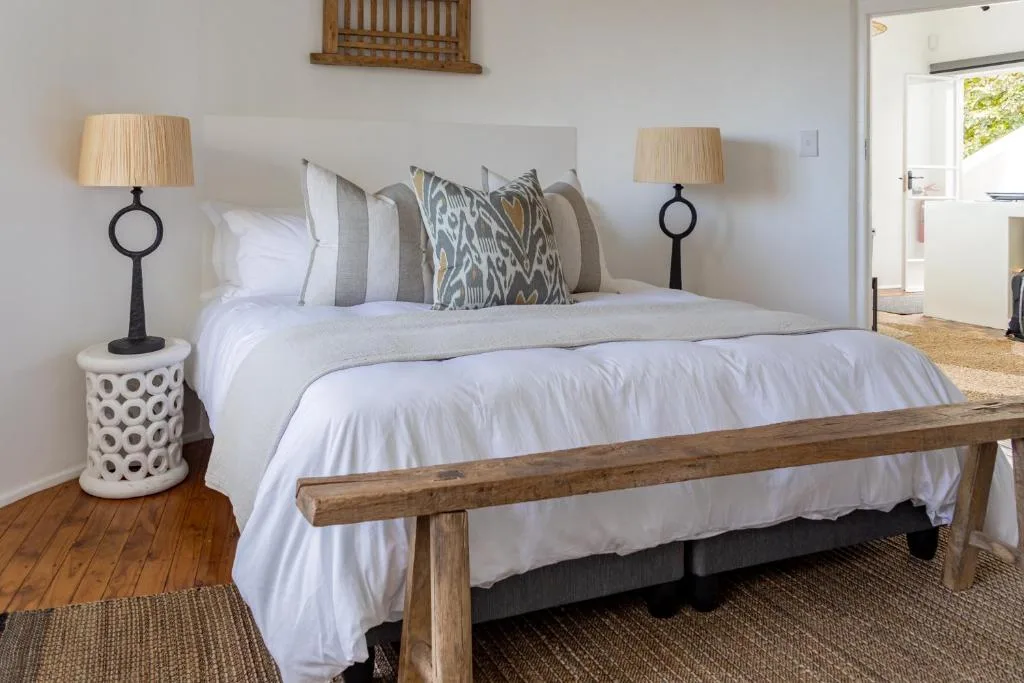 Spacious bedroom with wooden bed frame and white bedding, decorative pillows