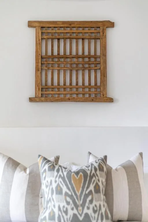 Wooden wall-mounted shelf with decorative patterned pillows below