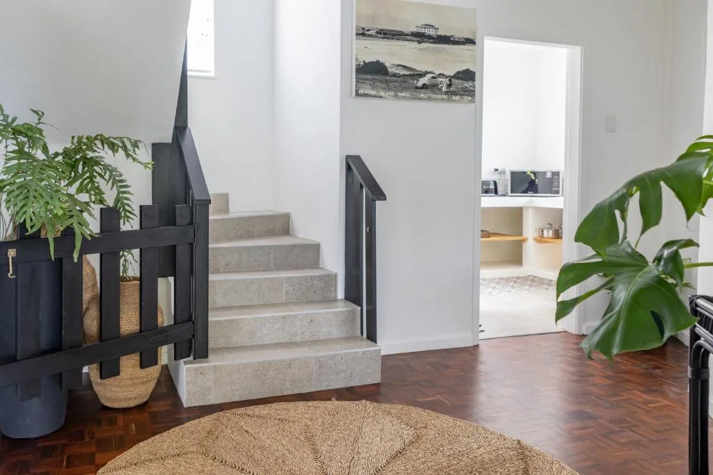Bright interior entryway with concrete stairs, potted plants, and coastal artwork